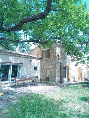 a stone house with chairs and tables in front of it at Sous un chêne bicentenaire in Lambesc