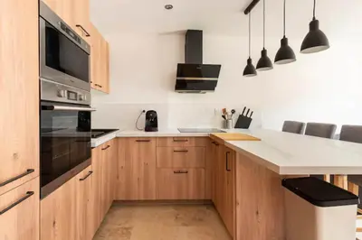 a kitchen with wooden cabinets and a stove top oven at Le marronnier 3: Superbe appart au coeur de la petite venise in LʼIsle-sur-la-Sorgue