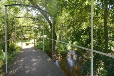 a wooden walkway over a river with a bridge at Mini gite foulon in Crillon-le-Brave