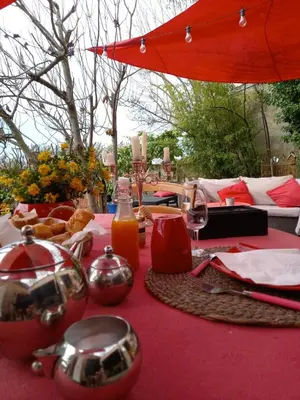 a table with a red table cloth with food and drinks at Le jardin de Sabine in Éguilles