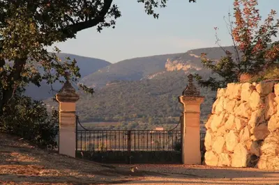 a gate with a stone wall with a mountain in the background at Domaine Perréal Les Gîtes in Gargas
