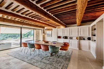 a kitchen with a wooden ceiling and a table and chairs at Le Mas Victoria in Gordes