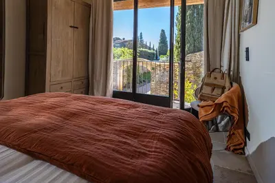 a bedroom with a large bed and a large window at Le Mas Luca in Gordes
