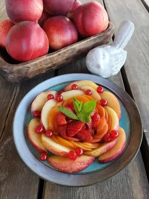 a plate of fruit on a table with a bowl of apples at La Bastide Neuve in Joucas