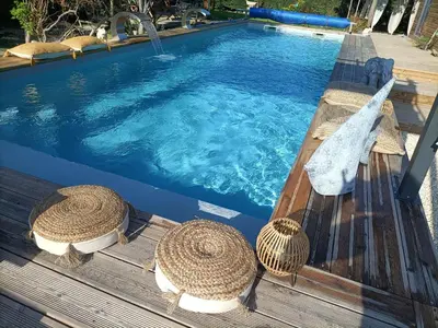 a swimming pool with two straw hats on a wooden deck at Cocoon inn&Spa in Saint-Saturnin-les-Avignon