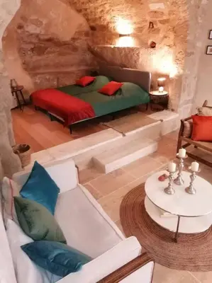 a bedroom with a bed and a couch and a table at La Maison d’Helene & Antoine à Bonnieux XII siècle in Bonnieux