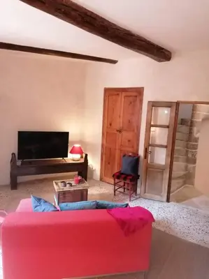 a living room with a pink couch and a tv at La Maison d’Helene & Antoine à Bonnieux XII siècle in Bonnieux