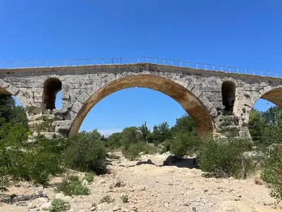 an old stone bridge with two arches on a hill at La Maison d’Helene & Antoine à Bonnieux XII siècle in Bonnieux