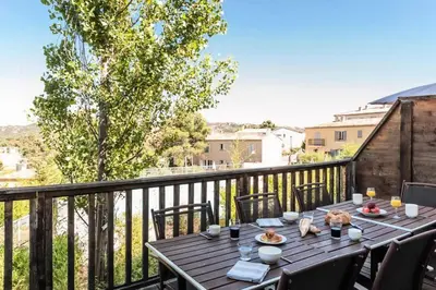 a table on a balcony with a view of a city at Les Coteaux de Pont Royal en Provence - maeva Home - Maison 3 Pièces 6 Personnes - Sélection MAE-7944 in Mallemort
