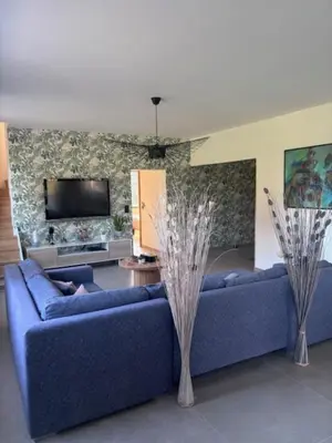 a living room with a blue couch and a tv at Maison contemporaine - grand jardin et piscine privée in LʼIsle-sur-la-Sorgue