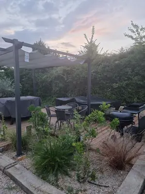 a patio with tables and chairs under a pergola at Une Oasis au Pays de Cézanne in Aix-en-Provence