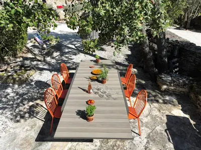 a long wooden table with orange chairs and plants at La Borie Oubliée in Gordes