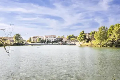 a view of a lake with houses in the background at Les Maisons de Pont Royal en Provence - maeva Home - Maison 3 pièces 6 personnes - Sélection MAE-2277 in Mallemort