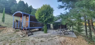 a wooden cabin with a table and a picnic table at Aurel inattendu in Aurel