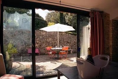 a patio with an umbrella and a table with chairs at Le Clos des Amandiers in Simiane-la-Rotonde