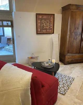 a living room with a red couch and a table at Les Remparts de Lauris Coeur Médiéval et Patio in Lauris