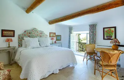 a bedroom with a white bed and a table and chairs at Le Clos des Rosiers in Gordes
