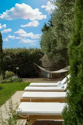 a row of white benches with a hammock in a garden at Le Clos des Rosiers in Gordes