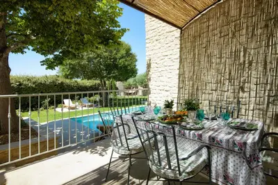 a table and chairs on a patio with a pool at Le Clos des Rosiers in Gordes
