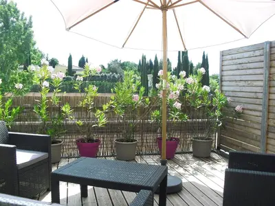 a patio with a table with an umbrella and potted plants at Studio à Deux Pas d'Aix in Aix-en-Provence