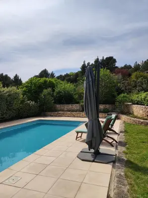 an umbrella and chairs next to a swimming pool at GITE AUX 4 SAISONS DU COLORADO PROVENÇAL - 3 ÉTOILES - Rustrel in Rustrel