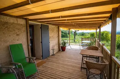 a wooden deck with chairs and a table at Maison en campagne avec vues panoramiques - close to a lake in La Tour-dʼAigues