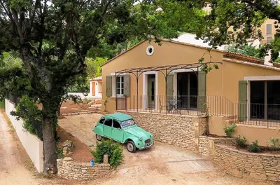 an old green car parked in front of a house at La Bohème à Lacoste in Lacoste