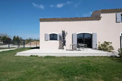 a white building with a patio with a table and chairs at Maison Réglisse du MAS LOU CAPY in Salon-de-Provence