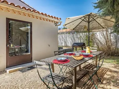 a table with chairs and an umbrella on a patio at Holiday Home La Campagne des Ocres by Interhome in Rustrel