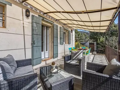 a patio with wicker furniture and an umbrella at Holiday Home La Campagne des Ocres by Interhome in Rustrel
