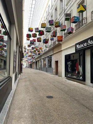 an empty street in a shopping mall with colorful umbrellas at Appartement climatisé avec cour en centre ville in Carpentras