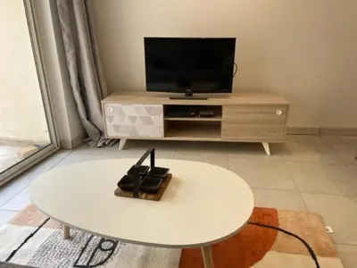 a living room with a white table and a tv at Appartement climatisé avec cour en centre ville in Carpentras