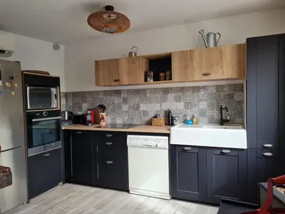 a kitchen with black cabinets and a white sink at Lumineux Duplex au coeur de l'Isle in LʼIsle-sur-la-Sorgue