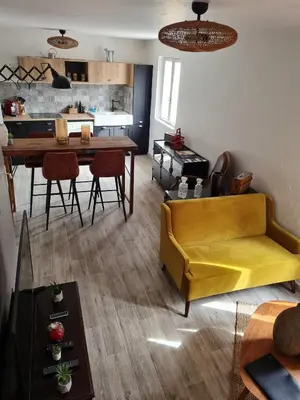 a living room with a yellow couch and a table at Lumineux Duplex au coeur de l'Isle in LʼIsle-sur-la-Sorgue