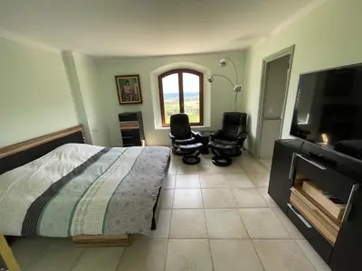 a bedroom with a bed and two chairs and a television at BASTIDE DU DEFENDS in Pertuis