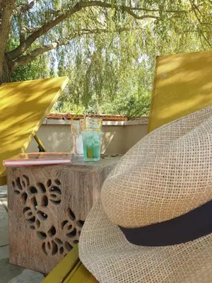 a table and a chair and a table with a drink at Mas des muses in LʼIsle-sur-la-Sorgue
