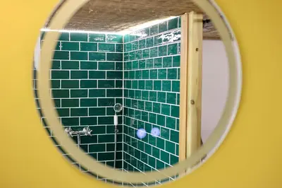 a mirror reflection of a green tiled bathroom at Mas des muses in LʼIsle-sur-la-Sorgue