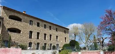 a large brick building with a fence in front of it at Appartement 3P Lubéron in Viens