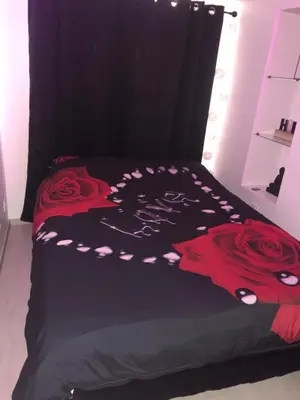 a black bed with red roses on it at Appartement Love room avec jacuzzi et hammam privatisé Lieu insolite en amoureux Spa détente assurée avec de doux massages en options sur demande in Orgon