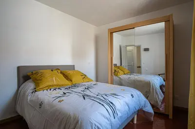 a bedroom with a bed with yellow pillows and a mirror at Maison avec jardin proche du centre-ville Isle-sur-la-Sorgue in LʼIsle-sur-la-Sorgue