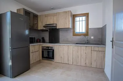 a kitchen with wooden cabinets and a stainless steel refrigerator at Maison avec jardin proche du centre-ville Isle-sur-la-Sorgue in LʼIsle-sur-la-Sorgue