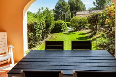 a wooden table in a room with a view of a yard at Village Pont Royal en Provence - maeva Home - Appartement décoré avec goût et climatisé 2 pièces 5 personnes - Prestige - super Home MAE-1144 in Mallemort