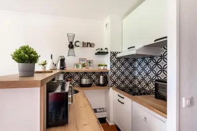 a kitchen with white cabinets and a black and white wallpaper at Village Pont Royal en Provence - maeva Home - Appartement décoré avec goût et climatisé 2 pièces 5 personnes - Prestige - super Home MAE-1144 in Mallemort