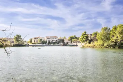 a view of a lake with houses in the background at Village Pont Royal en Provence - maeva Home - Appartement cosy et climatisé 3 pièces 6 personnes - Prestige - super Home MAE-3914 in Mallemort