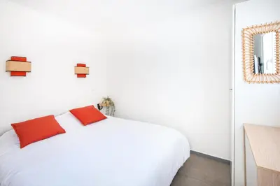 a bedroom with a white bed with two red pillows at Village Pont Royal en Provence - maeva Home - Appartement cosy et climatisé 3 pièces 6 personnes - Prestige - super Home MAE-3914 in Mallemort