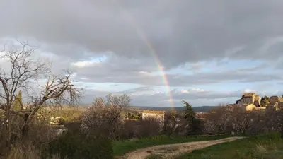 a rainbow in the sky with a house and a dirt road at Chambres d'Hôtes Le relais des marmottes en Luberon in Lagnes