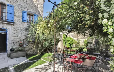 a patio with a table and chairs under a tree at Chambres d'Hôtes Le relais des marmottes en Luberon in Lagnes
