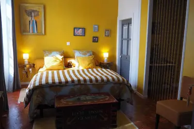 a bedroom with a bed with yellow walls at Chambres d'Hôtes Le relais des marmottes en Luberon in Lagnes