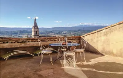 a table and chairs on a balcony with a church at Cozy Apartment In Bonnieux With Kitchen in Bonnieux