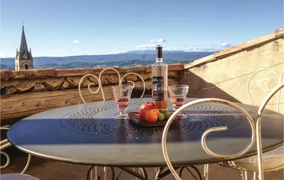 a table with a bottle of wine and fruit on a balcony at Cozy Apartment In Bonnieux With Kitchen in Bonnieux